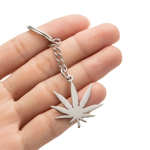 Polished silver stainless steel cannabis leaf pendant keychain held in hand