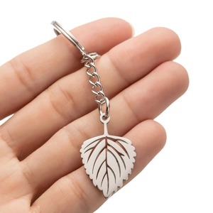 Polished stainless steel leaf keychain with intricate hollowed veins in a hand display