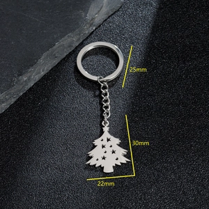 Stainless steel Christmas tree keychain with star cutout on a dark textured surface