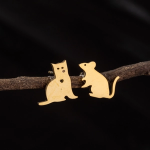 Asymmetric matte gold cat and mouse stainless steel stud earrings on a dark wood branch