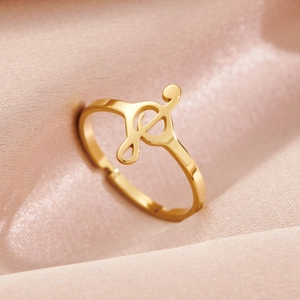 Gold treble clef musical note open ring on elegant pink silk fabric background