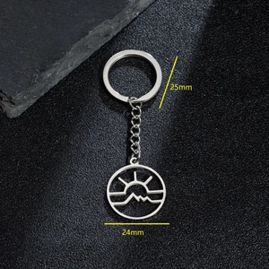 Stainless steel keychain with hollow sun and mountain pendant on a black textured background