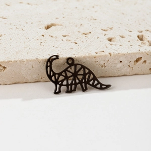 Detail of a matte black dinosaur hollow pendant on a natural travertine stone surface
