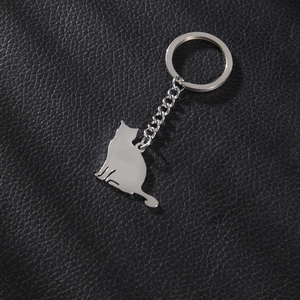 Porte-clés chat en métal argenté poli sur un support de fond en cuir noir élégant