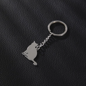 Détail du porte-clés chat en métal argenté poli sur un fond en cuir noir texturé