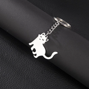Vue détaillée d'un porte-clés chat en métal poli sur un fond de cuir noir de haute qualité