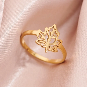 Golden adjustable maple leaf ring with cutout design on an elegant pink satin background