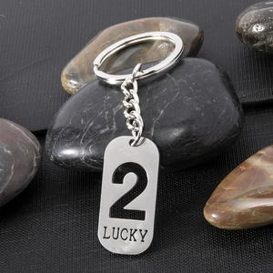 Close-up of a brushed stainless steel dog tag keychain with hollow number 2 and lucky engraving