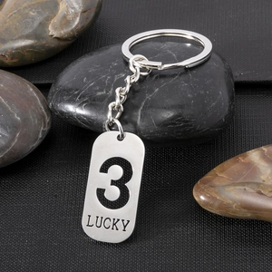 Detailed macro shot of silver lucky number 3 keychain on a textured black background