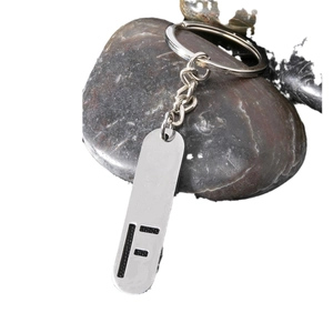 Silver stainless steel keychain with hollow rectangular letter F pendant on dark pebbles