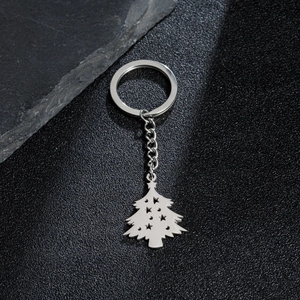 Silver stainless steel Christmas tree keychain with star cutout on black textured background