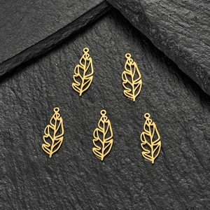 Macro view of five 18K gold-plated hollow leaf pendants on a dark stone background