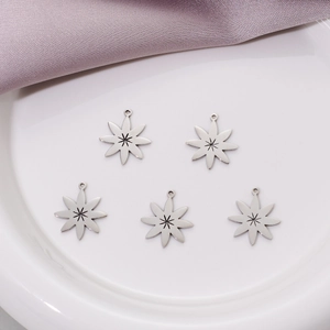 Five stainless steel octagonal star pendants with sunburst pattern on a white plate