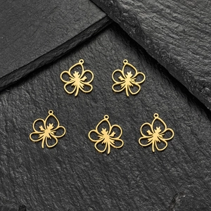 Detail of five gold hollow flower pendants with hanging rings on black slate background