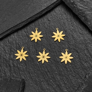 Set of five gold stainless steel starburst charms with radial texture on black stone