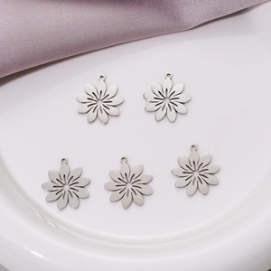 Five pieces of matte stainless steel flower charms for DIY jewelry making on white ceramic
