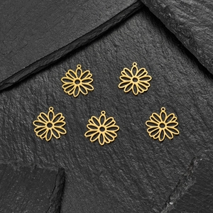 Cinq breloques marguerites en or 18 carats pour bijoux DIY sur fond de pierre texturée