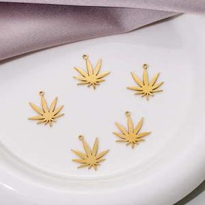 Five golden stainless steel maple leaf pendants for DIY jewelry making on white ceramic