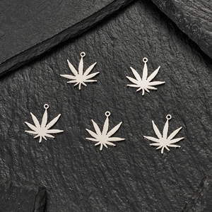 Five-piece silver cannabis leaf charms on black rock background for DIY jewelry