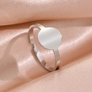Minimalist geometric stainless steel ring with flat round surface on pink silk fabric