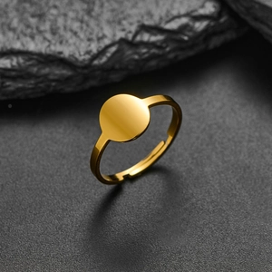Detail of minimalist gold adjustable ring with flat circular top on a stone background