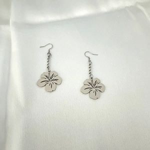 Detailed view of silver stainless steel five-petal flower drop earrings on white fabric