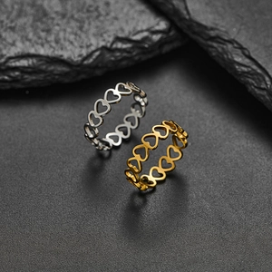Minimalist hollow heart-shaped rings in silver and gold finish on stone backdrop