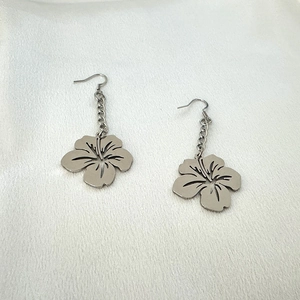 Detail of silver five-petal hibiscus flower earrings with hooks on white silk fabric