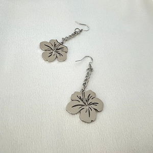 Matte silver hollow five-petal flower drop earrings in stainless steel on white fabric