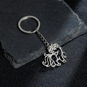 Cartoon unicorn keychain with hollow stainless steel pendant on black rock surface