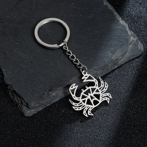 Modern geometric hollow crab keychain made of polished stainless steel on dark rock