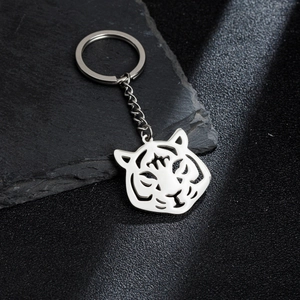 Porte-clés pendentif tête de tigre évidé en acier inoxydable sur fond de pierre noire