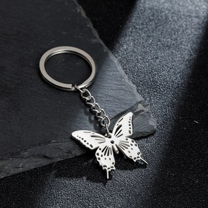 Polished stainless steel butterfly pendant keychain on a dark slate background