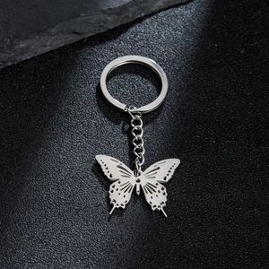 Minimalist stainless steel butterfly keychain with hollow wing design on dark rock surface