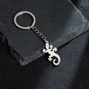 Polished stainless steel gecko lizard keychain pendant displayed on dark natural stone