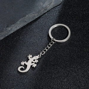 Polished stainless steel lizard gecko keychain pendant on black leather and stone background