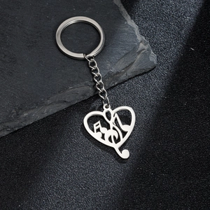 Silver stainless steel music note heart keychain on dark textured stone background