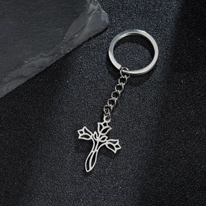 Artistic silver cross and rose flower pendant keychain on textured stone background