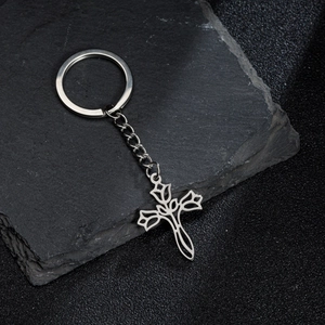 Silver stainless steel hollow rose cross keychain displayed on a grey textured stone slab