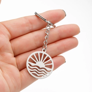Detailed shot of a stainless steel keychain with a sun and sea wave cutout pattern
