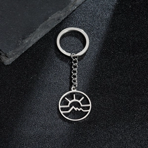 Detail shot of a minimalist hollow mountain sunrise pendant on a stainless steel keychain