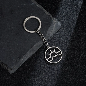 Polished silver stainless steel mountain and sunrise keychain on dark stone background