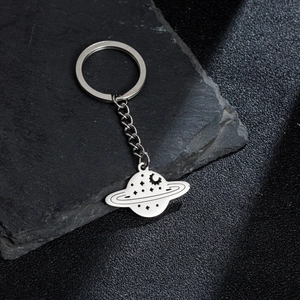 Polished stainless steel Saturn and Moon planet keychain with metal chain on slate rock