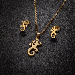 Set gioielli geco dorato con collana e orecchini a lobo su sfondo in pelle nera di lusso