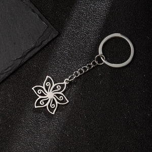 Polished stainless steel keychain with hollow flower pendant and scrollwork on black background