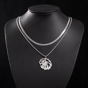 Close-up of layered snake chain and ring chain with a carved eagle head pendant