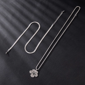Silver stainless steel layered necklace featuring a floral pendant on black leather texture