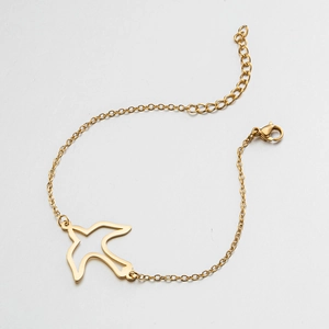 Detail of golden stainless steel bracelet featuring a minimalist hollow bird charm and lobster clasp