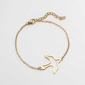 Detail of a minimalist gold bird pendant bracelet with adjustable link chain and lobster clasp