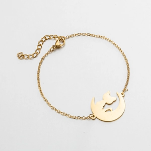 Detailed close-up of a golden moon and cat silhouette pendant on a delicate link bracelet